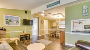 Un salon comprenant un canapé, une table basse, un téléviseur et un coin repas avec des chaises et une table.