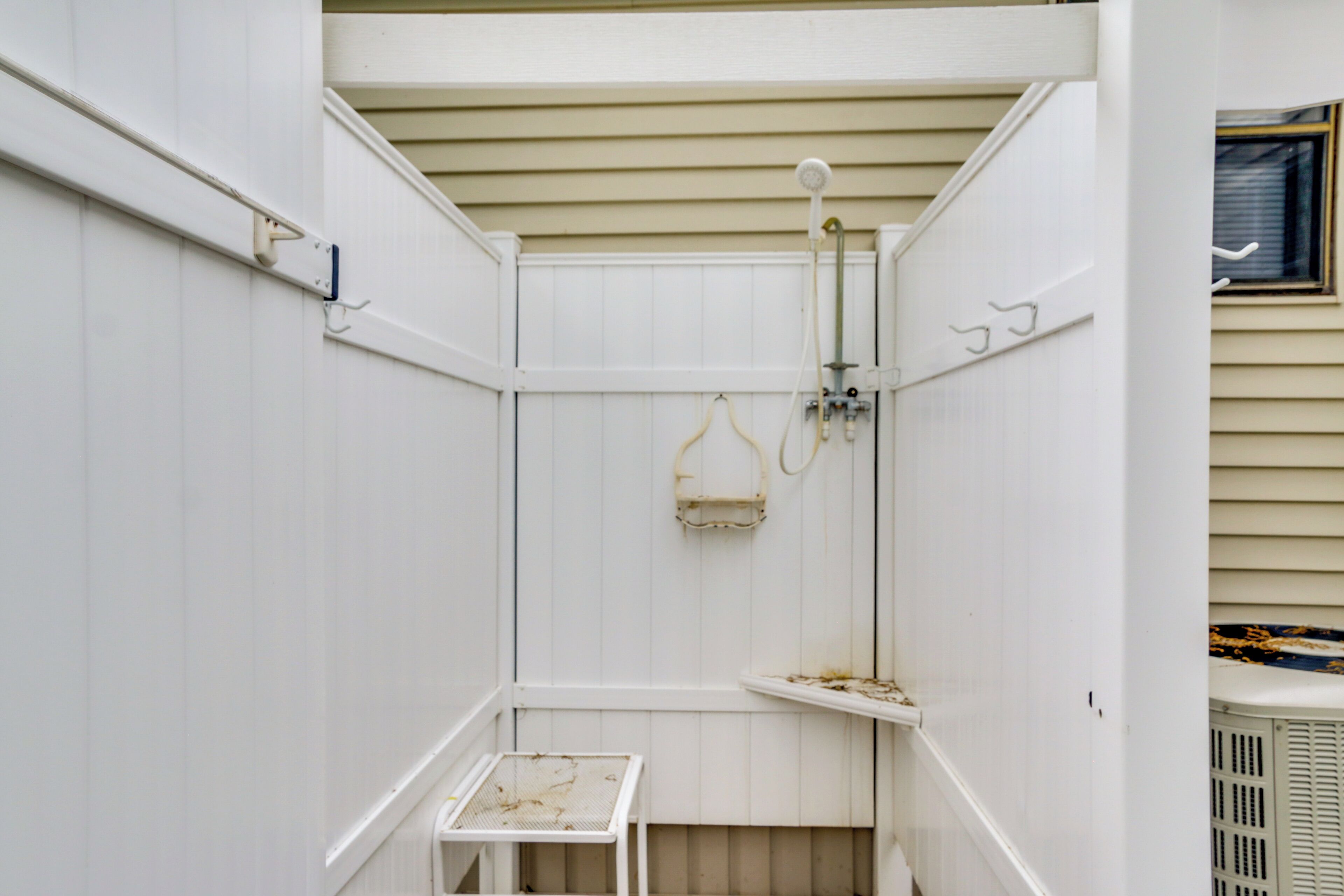 A small, enclosed shower area with a metal table and a hanging shower head.