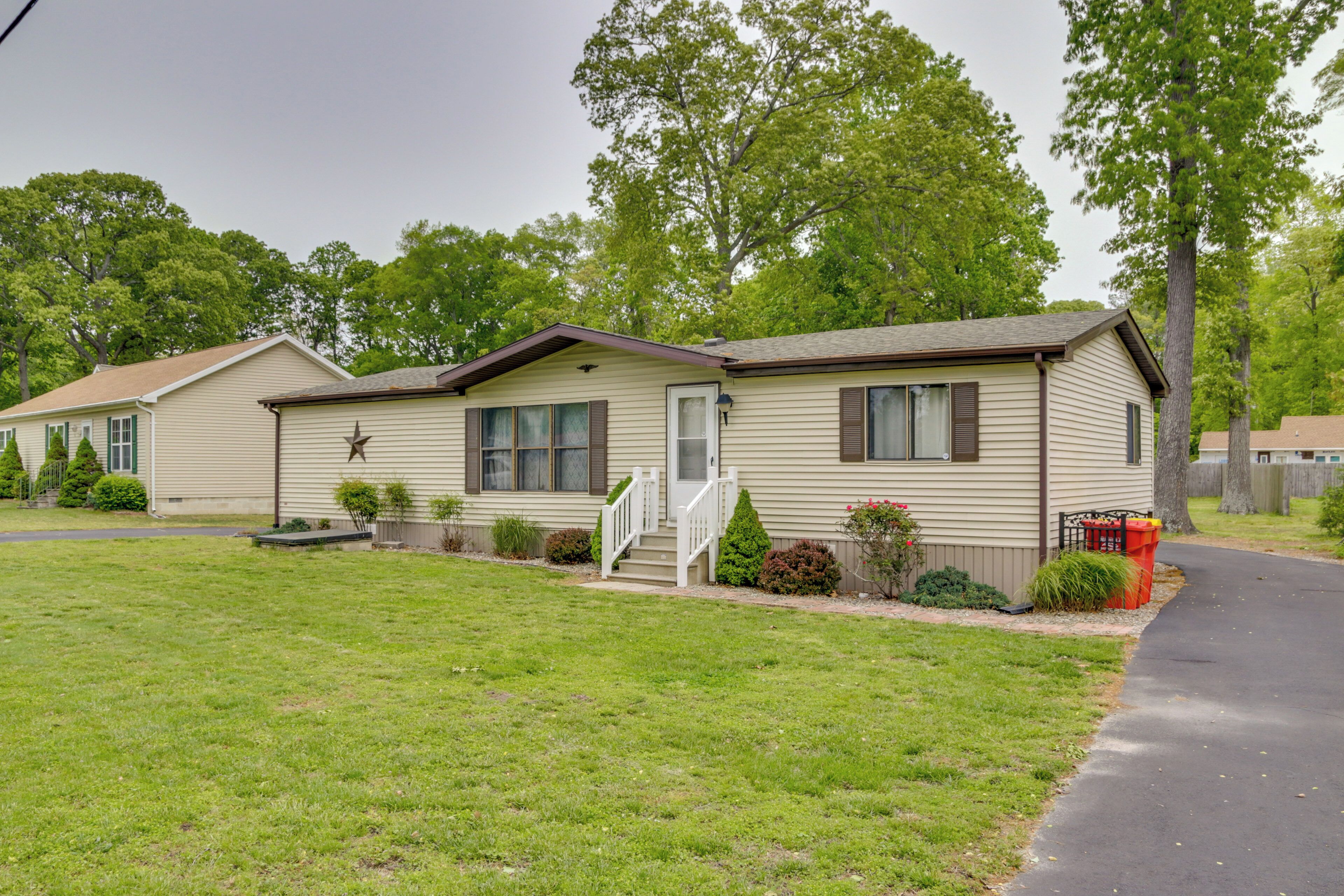 A single-story mobile home with a front porch, a small front yard, and a driveway.