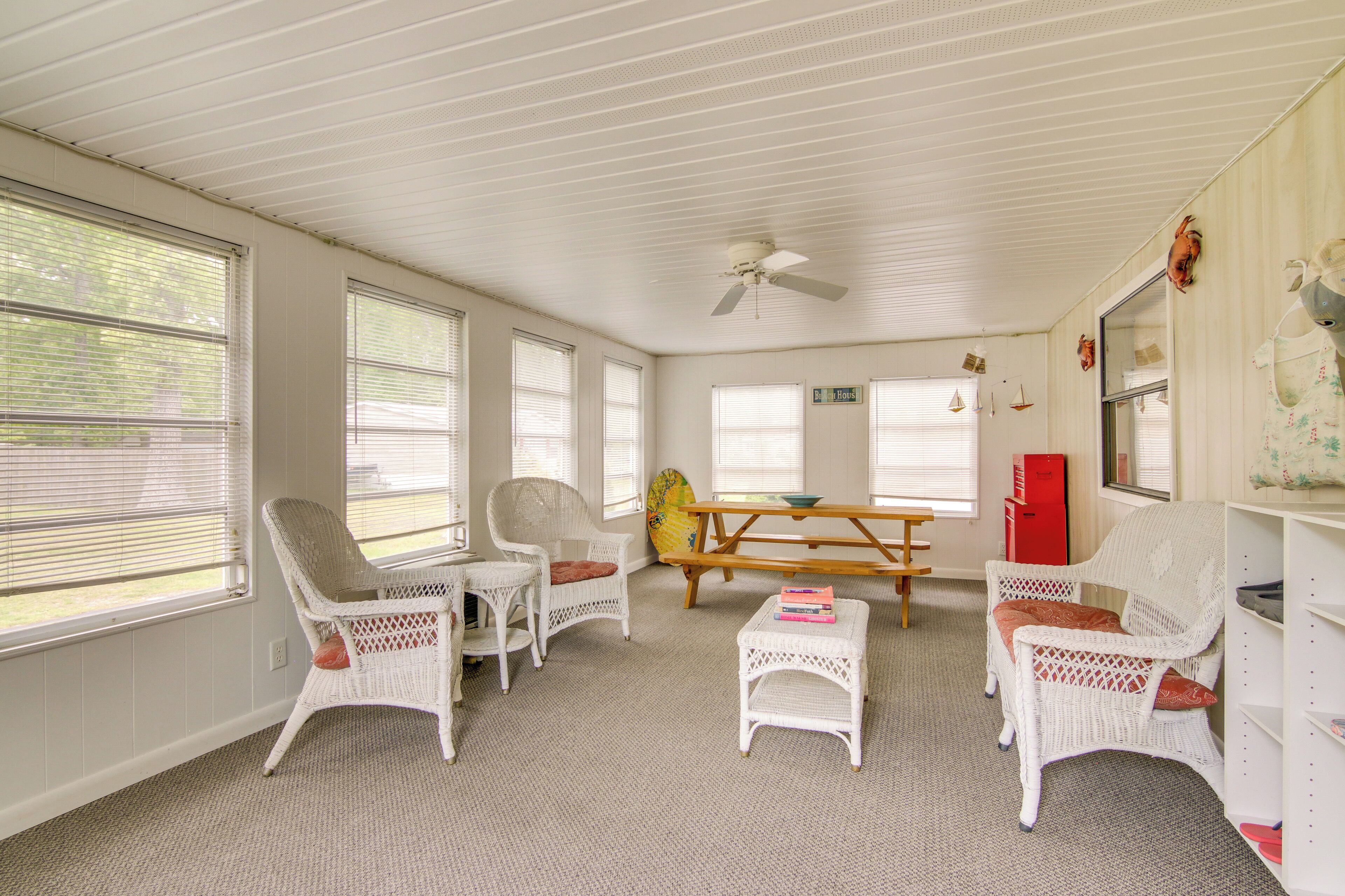 Una habitación con muebles de mimbre blanco, ventilador de techo y una mesa de picnic.