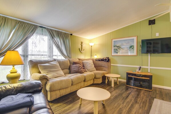 A living room with a sofa, two round tables, a TV, and a lamp. - Beachy Lewes Home w/ Outdoor Shower & Fire Pit! (Lewes)