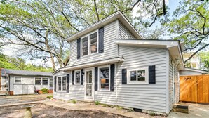 A two-story house with a front porch, a garage, and a wooden gate. - Chic Historic Myrtle Beach Cottage: Steps to Beach (Myrtle Beach)