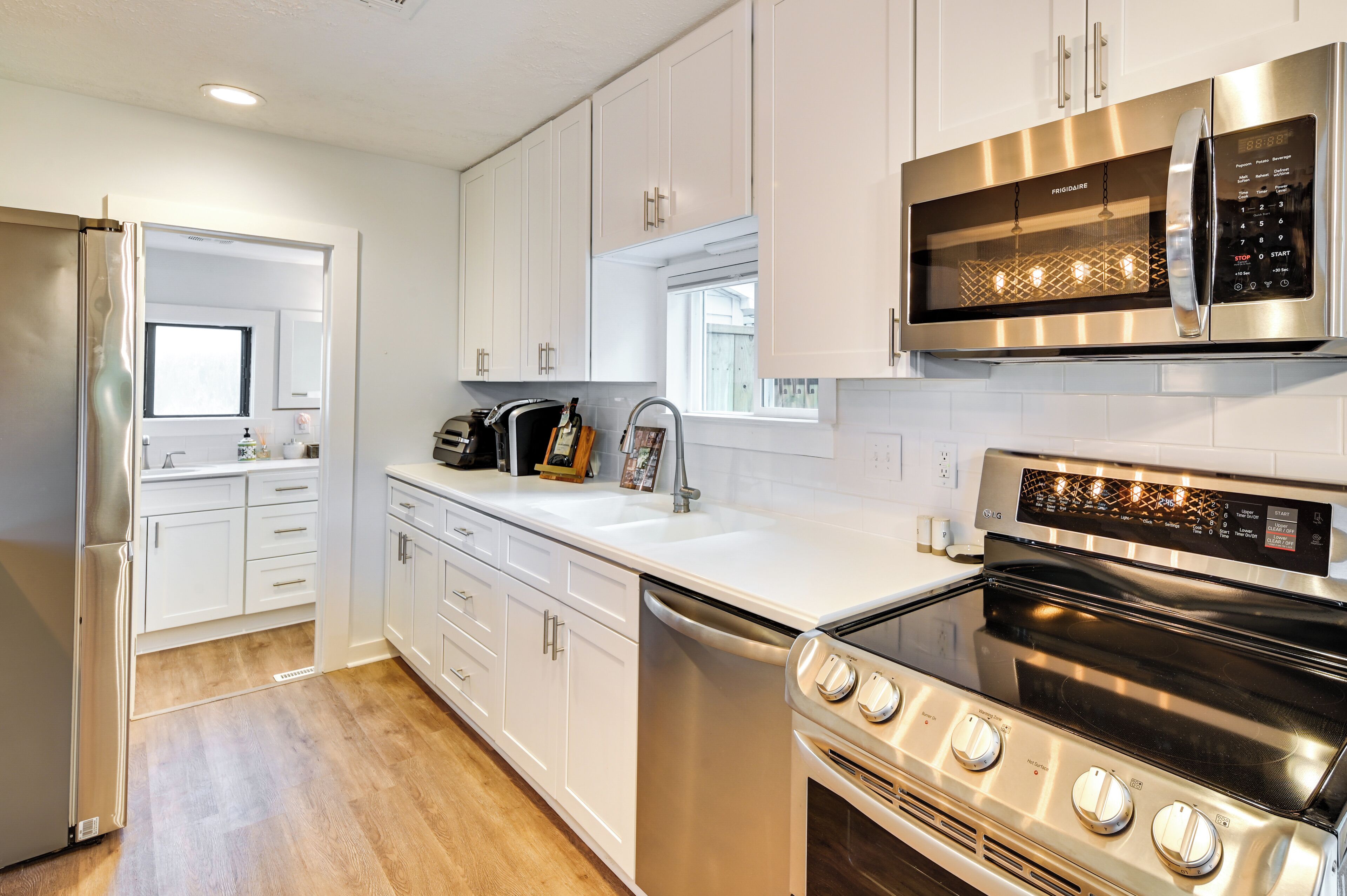 A modern kitchen with white cabinets, stainless steel appliances, a dishwasher, and a built-in oven.