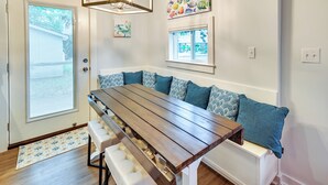 A dining area with a wooden table and bench seating, a chandelier, and artwork on the walls. - Chic Historic Myrtle Beach Cottage: Steps to Beach (Myrtle Beach)