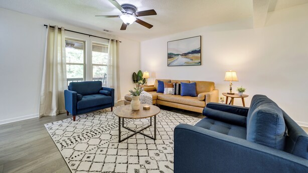 A living room with a ceiling fan, two sofas, a coffee table, and a rug. - Peaceful Candler Cabin w/ Private Hot Tub! (Candler)