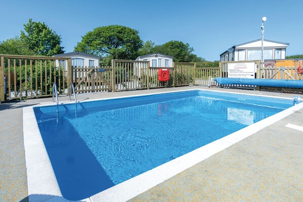 En swimmingpool med et træhegn, et redder-tårn og et skilt der angiver beredsservice.