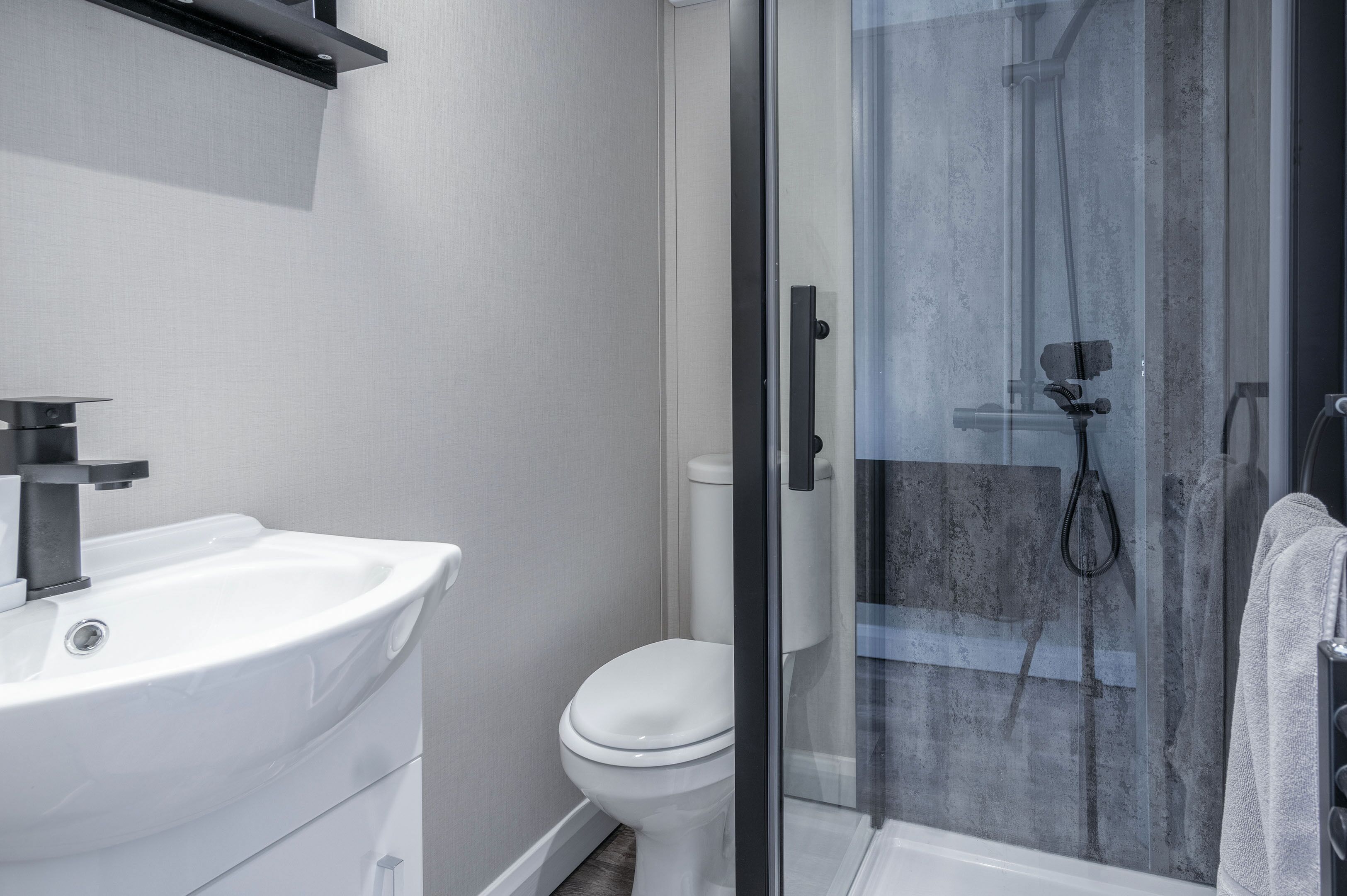 Een moderne badkamer met een witte wastafel, toilet en douchecabine.