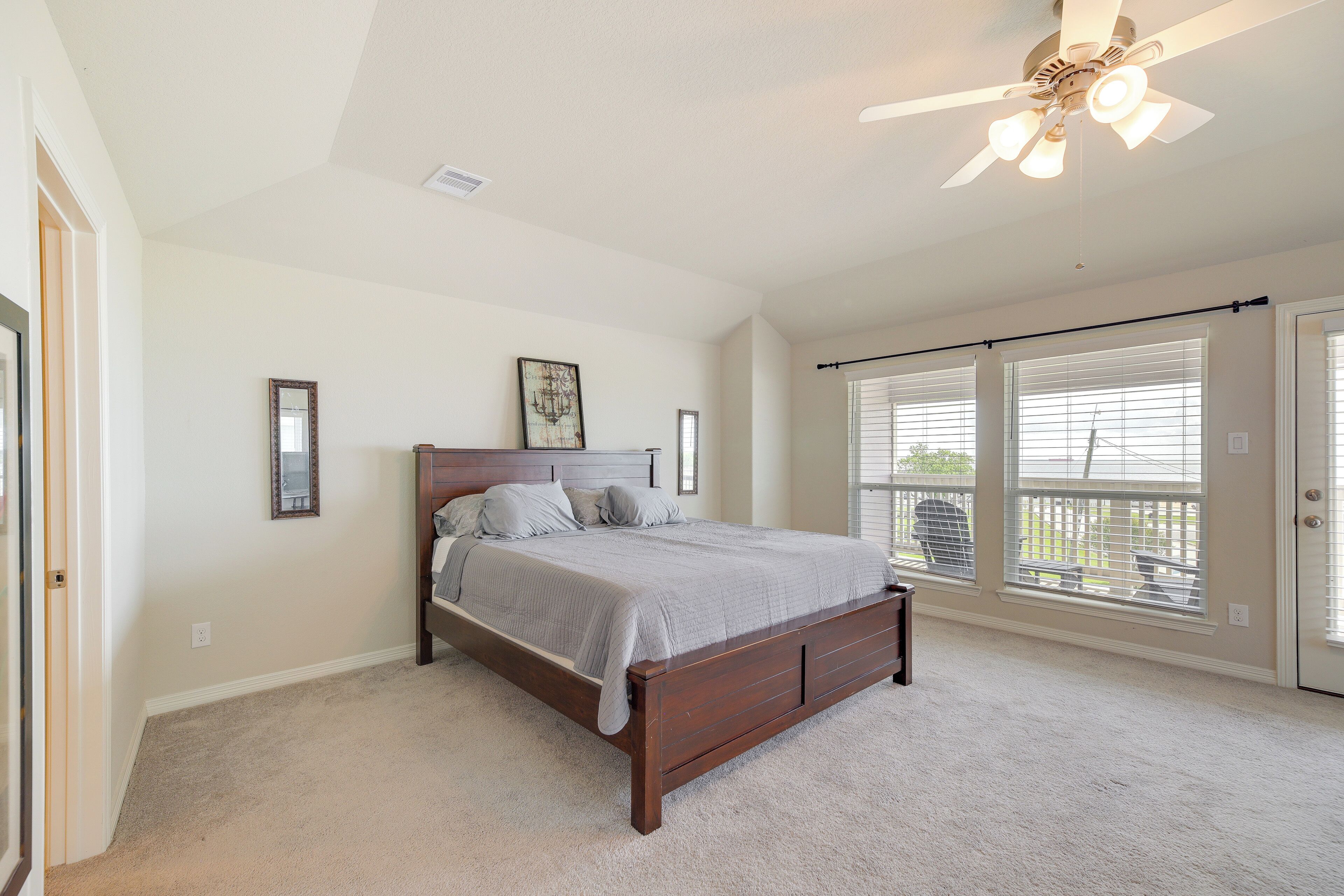 A bedroom with a large bed, a ceiling fan, and a view through the window.