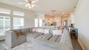 A spacious living room with a sectional sofa, a ceiling fan, and a kitchen area in the background. - Bay-view La Porte Home Rental: Steps to Beach! (La Porte)