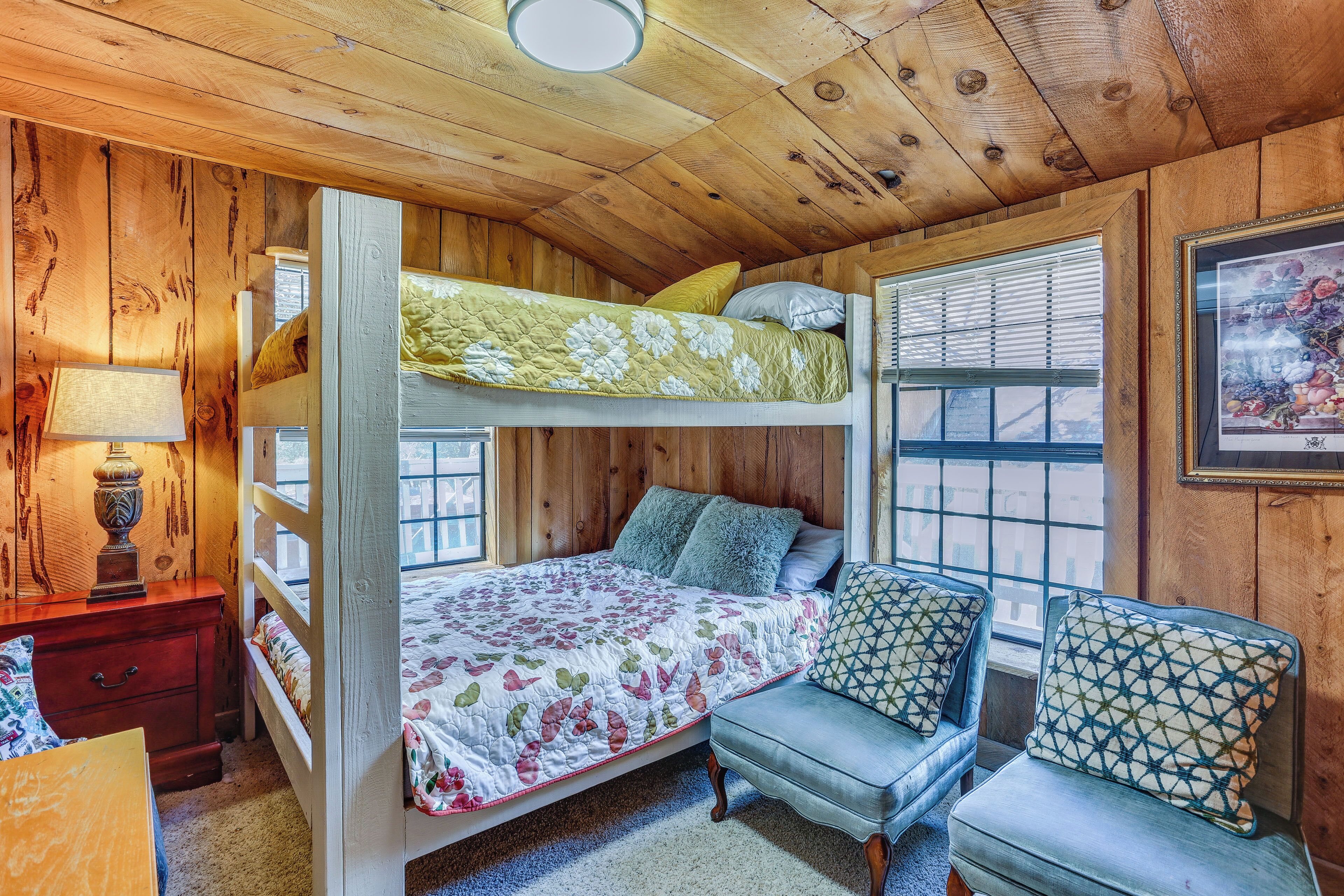 Une chambre avec un lit superposé, un plafond en bois, un bureau avec une lampe, une chaise et une fenêtre avec des stores.