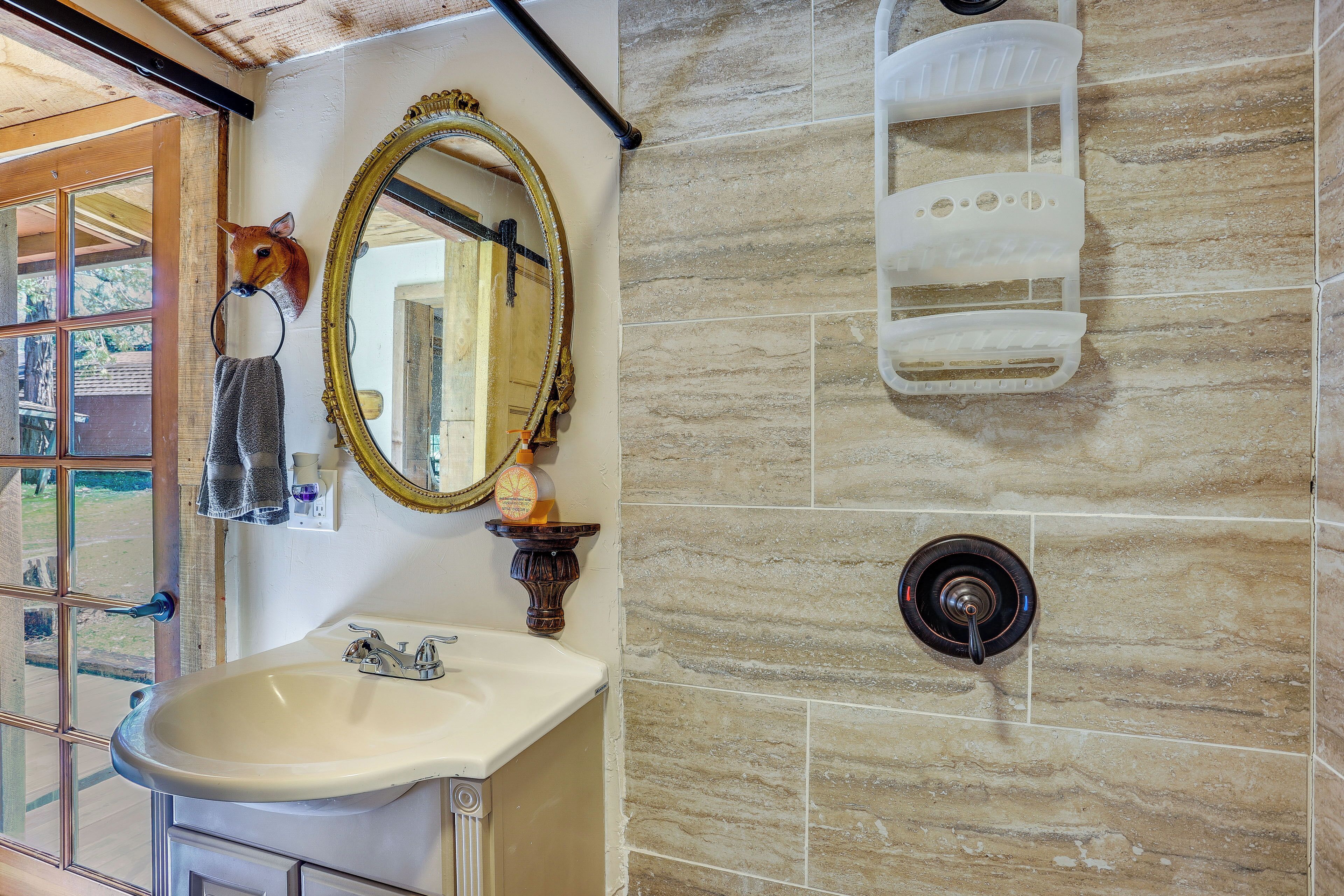 A bathroom with a sink, mirror, towel rack, and a shower area.