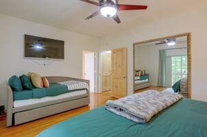 A bedroom with a bed, a sofa, a television, and a ceiling fan.