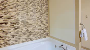 A bathroom with a tiled wall, a bathtub, and a towel rack.