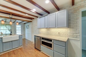 A kitchen with wooden beams, grey cabinets, a dishwasher, and an oven. - Charming New Bern Cottage w/ Grill & Fire Pit! (New Bern)