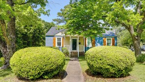 A house with a front porch, a pathway leading to the entrance, and two well-maintained bushes. - Charming New Bern Cottage w/ Grill & Fire Pit! (New Bern)