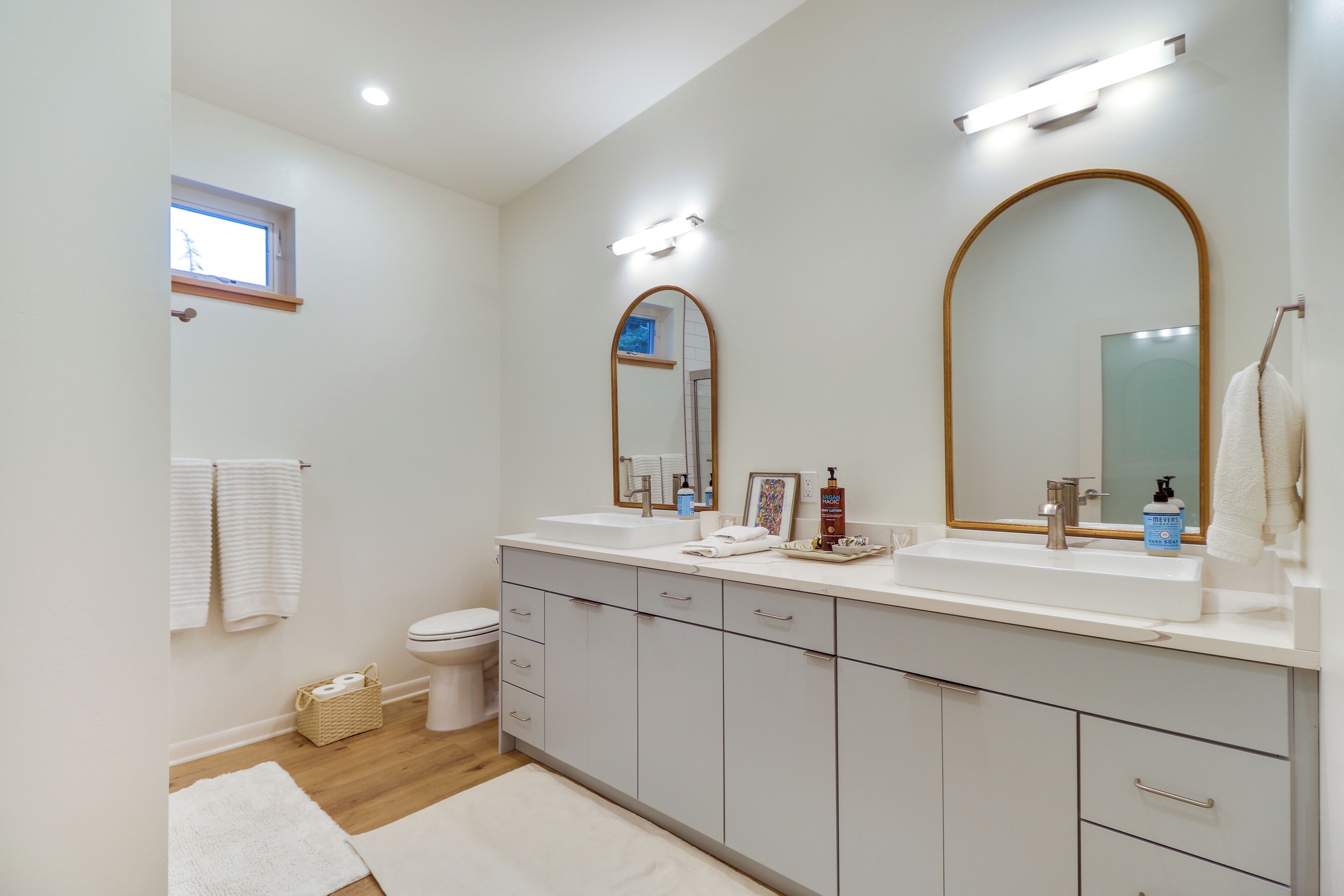 Un baño moderno con un espejo grande, un lavamanos y un inodoro.