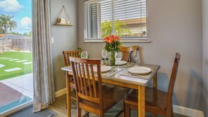 A dining area with a table set for four, a window with blinds, and a view of a green lawn. - Private Pool & Patio: Fort Lauderdale Home! (Fort Lauderdale)