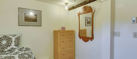 A bedroom with a bed, a wooden dresser, a mirror, and a framed picture on the wall.