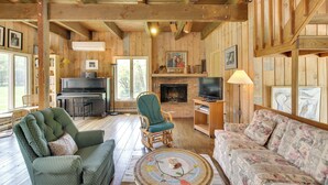 A cozy cabin interior with a piano, fireplace, and comfortable seating. - Serene Salisbury Rental Home on 26 Acres w/ Deck! (Falls Village)
