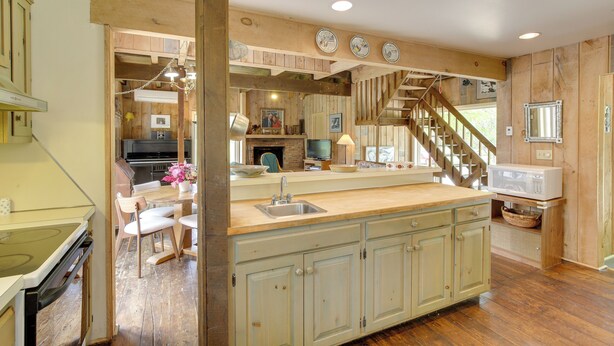 A kitchen with a wooden island, a built-in stove, and a dining area with chairs. - Serene Salisbury Rental Home on 26 Acres w/ Deck! (Falls Village)
