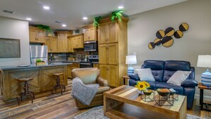 A modern kitchen with wooden cabinets, stainless steel appliances, and a dining area with a leather sofa and coffee table. - Raymondville Apartment w/ Patio: Near Lakes! (Raymondville)