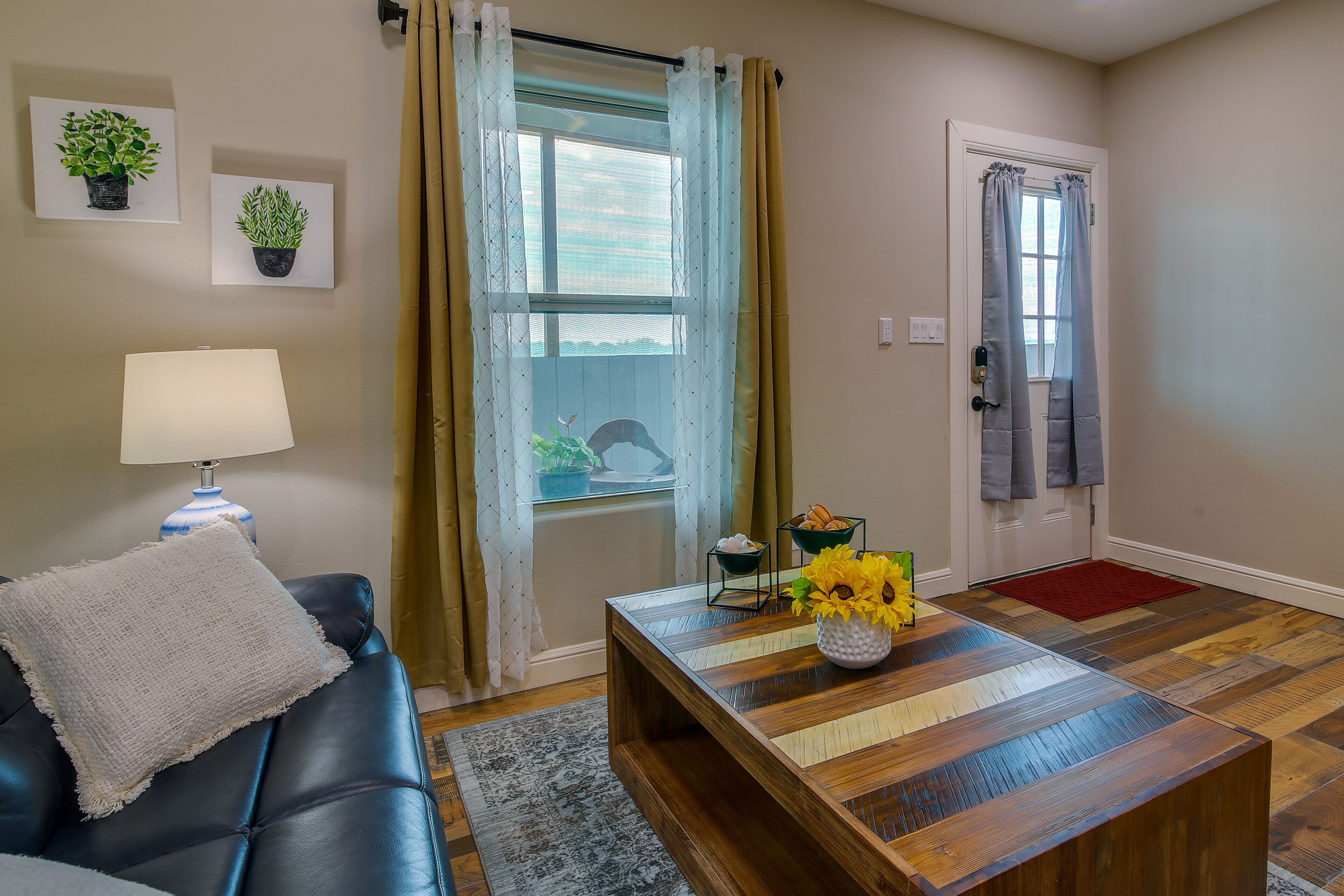 A living room with a sofa, a wooden coffee table, a lamp, and a door with curtains.