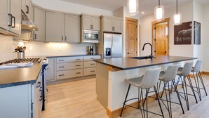 A modern kitchen with a central island, bar stools, stainless steel appliances, and pendant lighting. - Fraser Getaway w/ Deck Near Winter Park Resort! (Fraser)