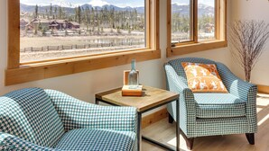 A room with two houndstooth patterned chairs, a small table with a vase, and a view of a mountainous landscape through large windows. - Fraser Getaway w/ Deck Near Winter Park Resort! (Fraser)