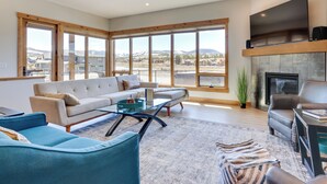 A spacious living room with a large window, a fireplace, and a flat-screen TV. - Fraser Getaway w/ Deck Near Winter Park Resort! (Fraser)
