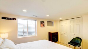Un dormitorio con cama, cómoda, silla, ventana y puerta.