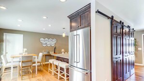 Una cocina moderna con un refrigerador de acero inoxidable grande, armarios de madera y una zona de bar.