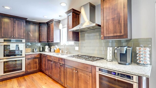 Una cocina moderna con armarios de madera oscura, electrodomésticos de acero inoxidable y encimera de granito.