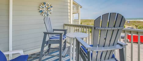 A covered outdoor area with two Adirondack chairs, a small table, and a decorative wall piece.