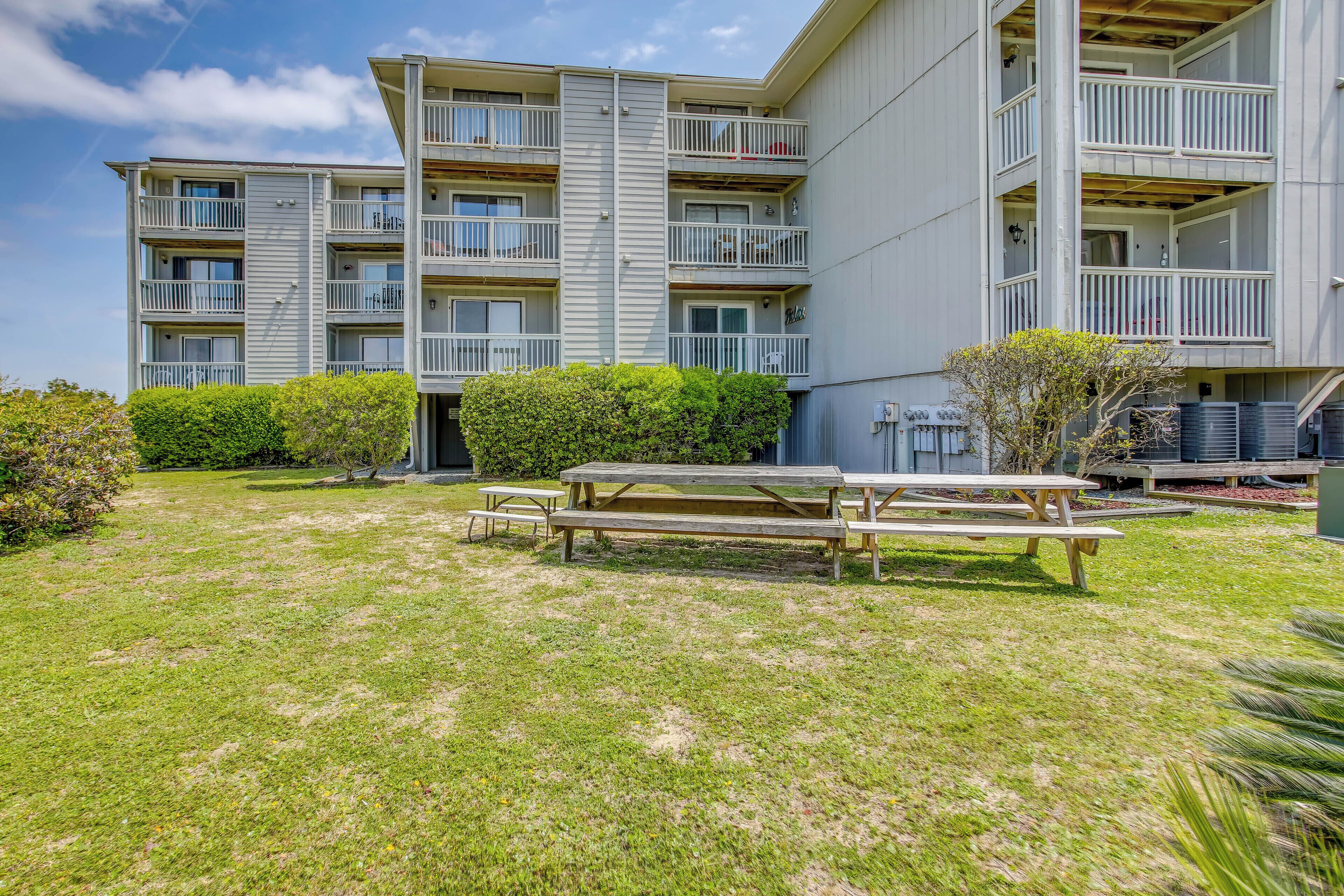 A multi-story residential building with balconies, a picnic table, and a well-maintained lawn.