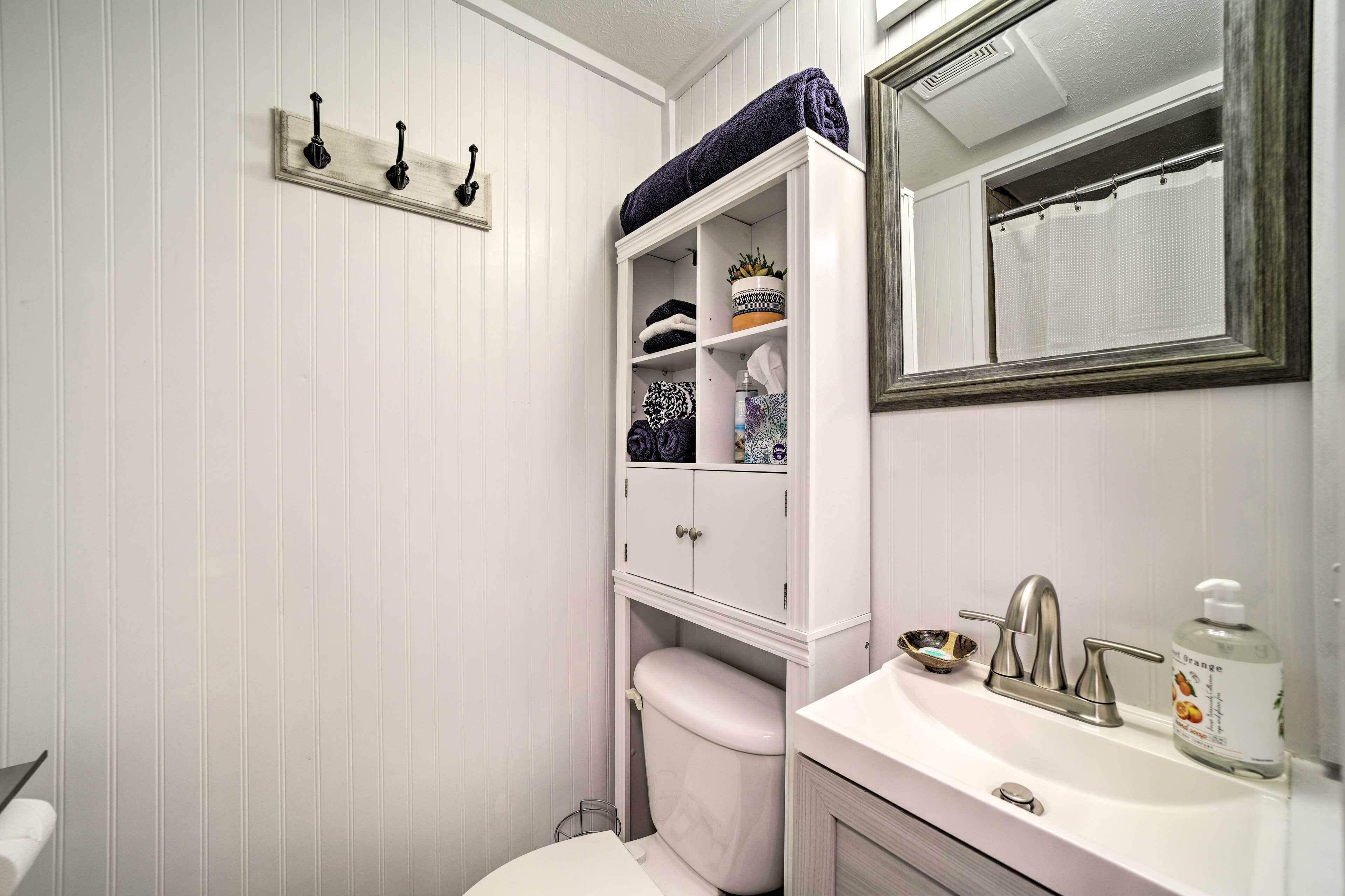 A bathroom with a white toilet, a sink with a faucet, a mirror, and a towel rack.