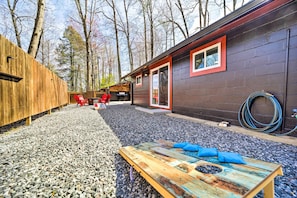 A rustic cabin with a gravel driveway, a wooden deck, and a metal table with cushions. - Multi-unit Brevard Vacation Rental With Patio! (Brevard)