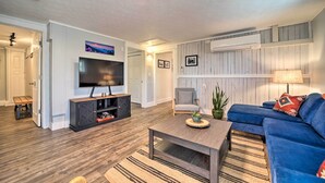 A living room with a TV, sofa, coffee table, and a wooden floor. - Multi-unit Brevard Vacation Rental With Patio! (Brevard)