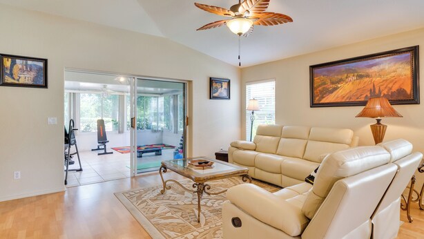 A spacious living room with a leather sofa, a glass coffee table, and a ceiling fan. - North Fort Myers Getaway w/ Resort Amenities! (North Fort Myers)