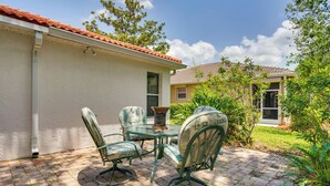 A patio with a table and chairs, a brick pathway, and a house with a red-tiled roof. - North Fort Myers Getaway w/ Resort Amenities! (North Fort Myers)