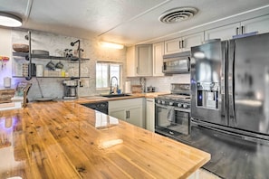 Une cuisine moderne dotée d’un plan de travail en bois, d’appareils électroménagers en acier inoxydable et d’un four encastré.
