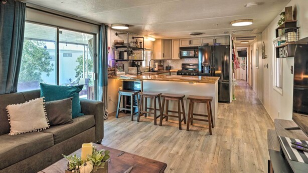 A modern kitchen with a central island, wooden bar stools, and a dining area with a wooden table.