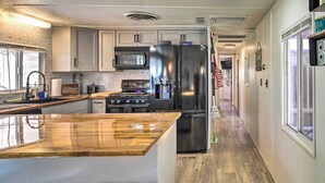 A kitchen with a wooden island, stainless steel appliances, and a view into the adjacent dining area.