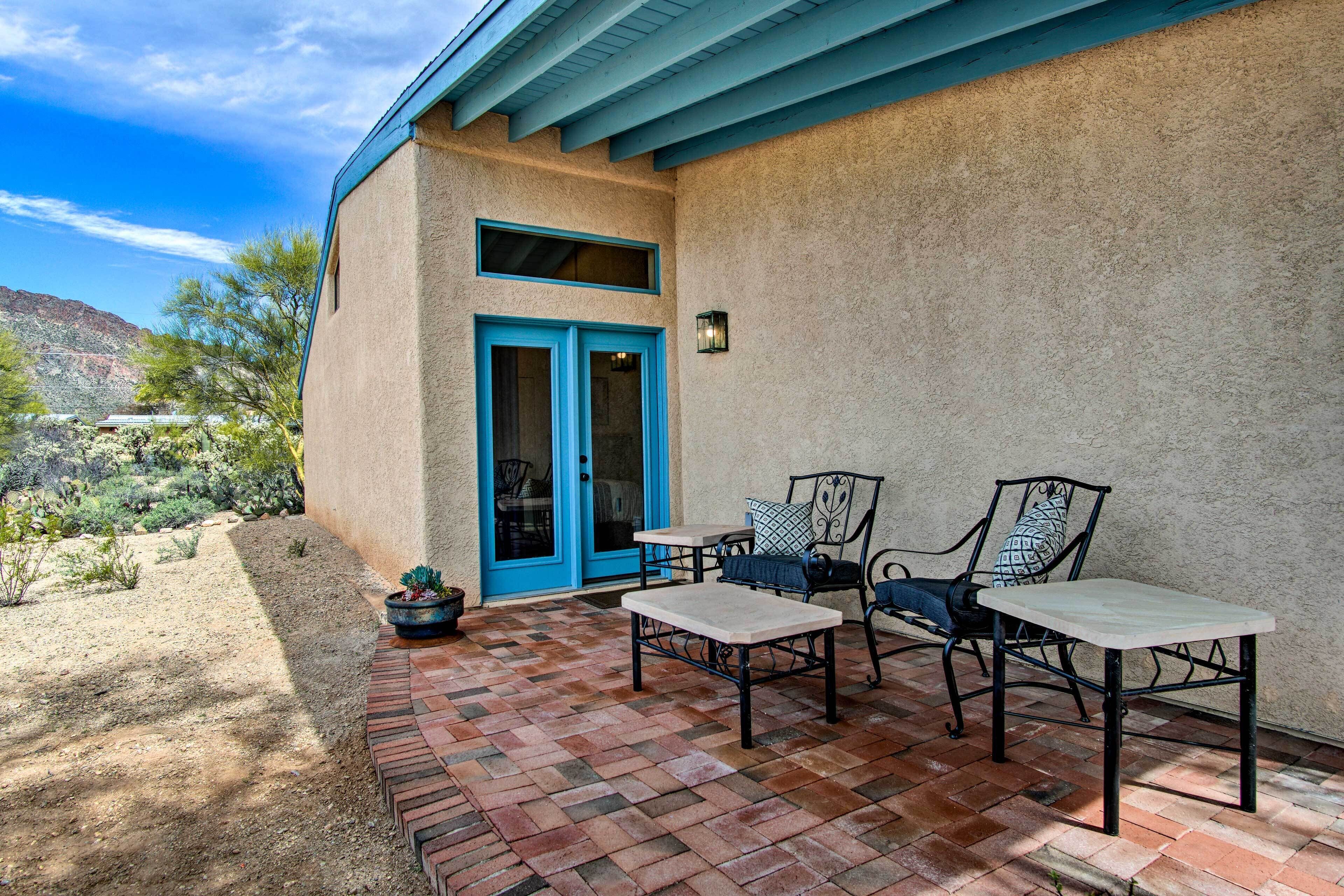 An outdoor patio with a brick floor, two tables, and two chairs.