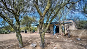 A rustic building with a blue roof, surrounded by trees and a gravel path.