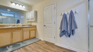 A modern bathroom with a wooden vanity, a large mirror, and a towel rack with two towels.