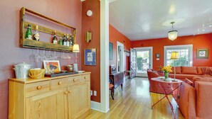 A kitchen with wooden cabinets, a wine rack, and a dining area with a red sofa and a table.