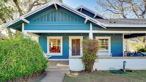 A two-story house with a blue exterior, a front porch, and a visible garden area.