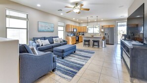 A modern living room with a sectional sofa, a kitchen area with wooden cabinets, and a ceiling fan. - Pool, Patio & Grill: San Tan Valley Escape! (San Tan Valley)
