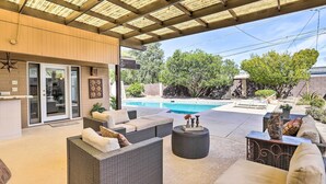 Eine überdachte Terrasse mit Korbmöbeln, einem Pool und einem Wasserfall.