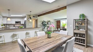 Eine moderne Küche mit weißen Schränken, einem Holztisch und Barhocker.